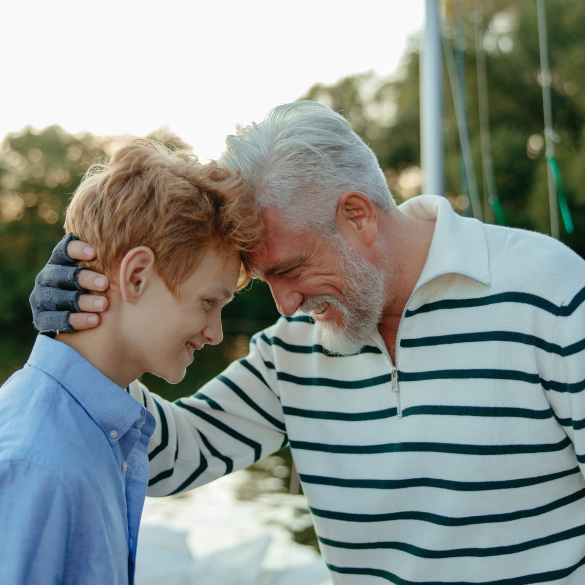 Nachhaltige Energie für kommende Generationen Älterer Mann und Junge berühren lächelnd die Stirn – Sinnbild für generationsübergreifende Nachhaltigkeit