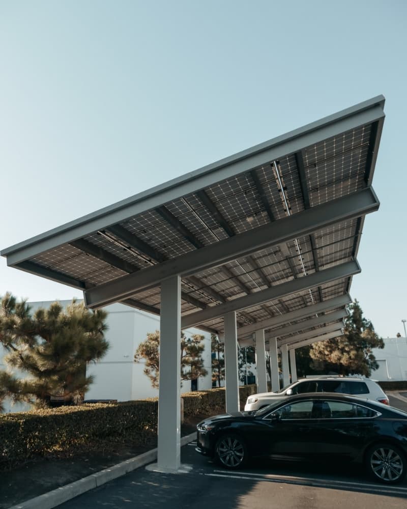 Photovoltaik-Carport auf Parkplatzanlage Autos parken unter einer überdachten PV-Anlage mit schrägem Solardach bei Tageslicht