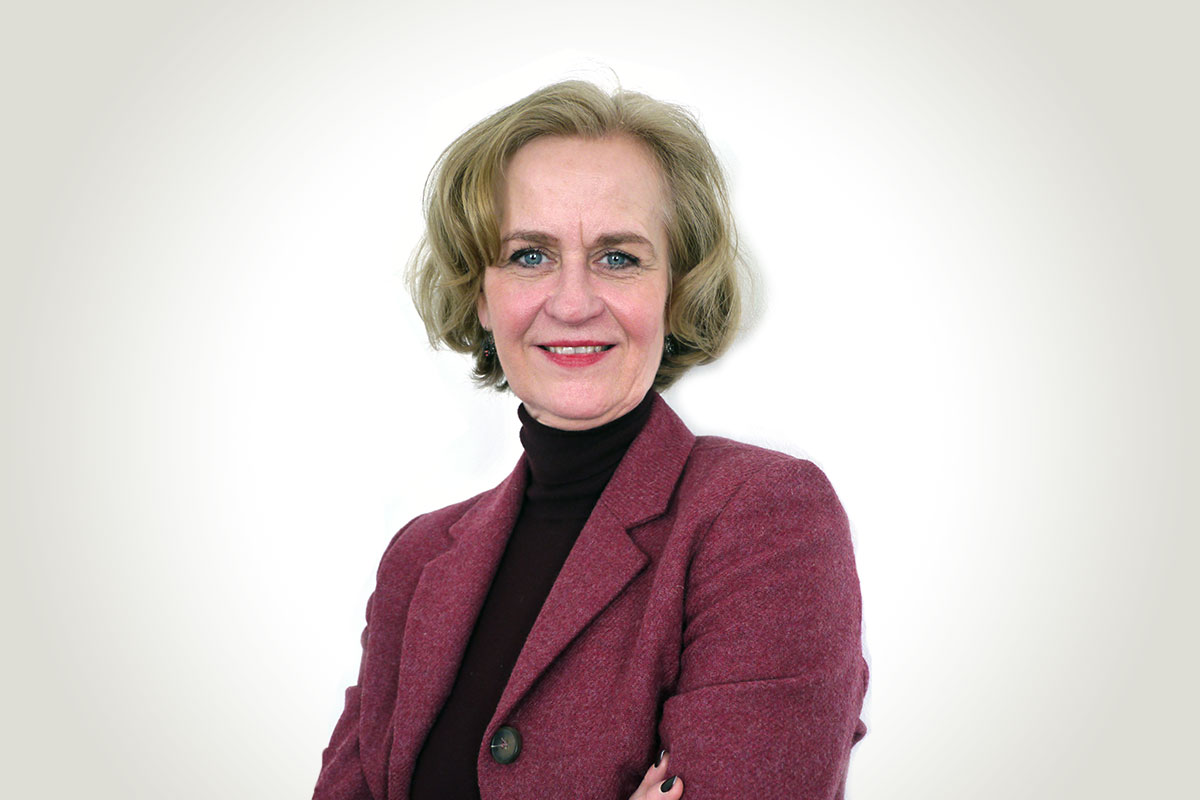 Ansprechpartnerin für Beratung und Kundenservice – Frau Rose Porträt einer lächelnden Frau mit kurzem blondem Haar im roten Blazer vor hellem Hintergrund