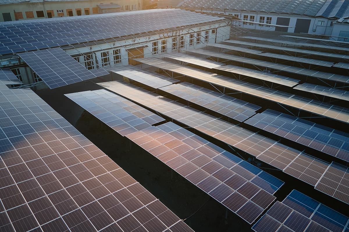 Solaranlagen zur Eigenversorgung auf Industriedach Große PV-Fläche auf einem Gewerbedach im Sonnenuntergang, symbolisiert Eigenversorgung mit Solarstrom